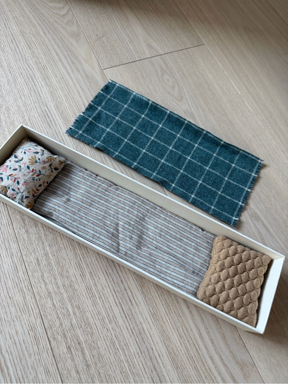 Maileg matchbox that is furnished with a mattress, pillows, and a blanket